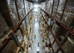 Shelves with goods and workers of warehouse in aisle